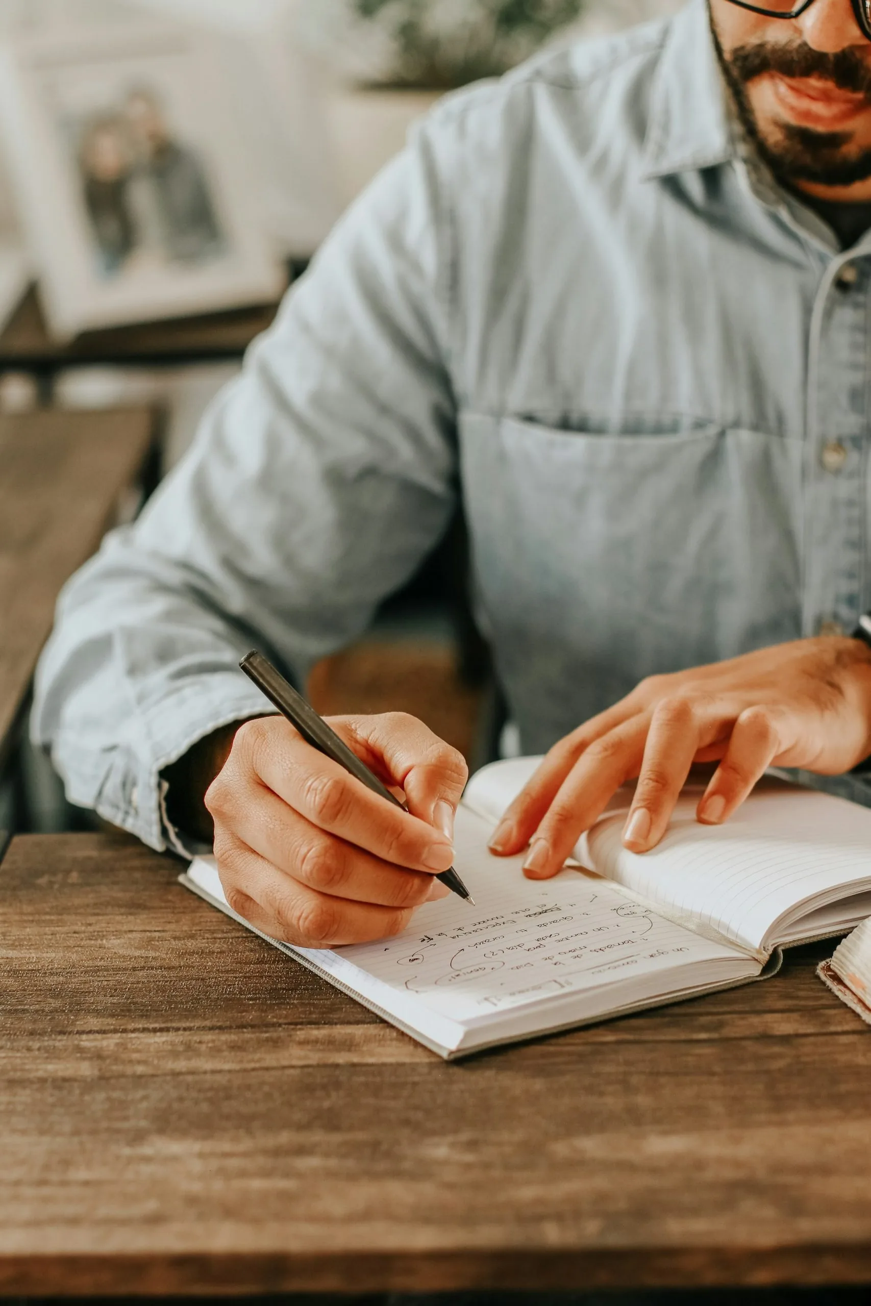An adult writing while studying at a desk